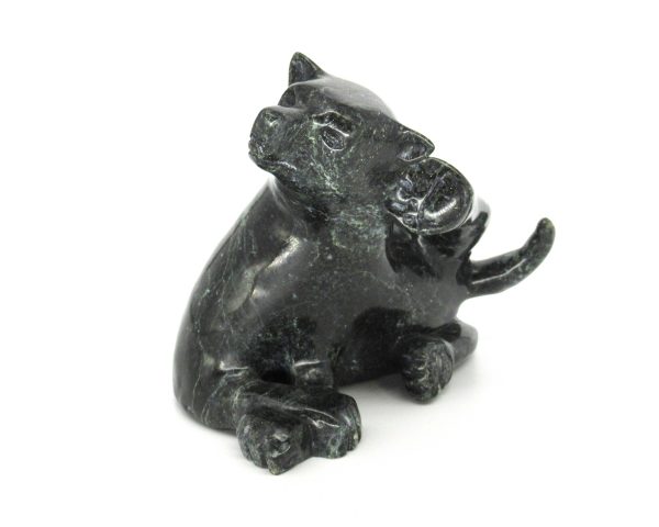 Wolf carving made from serpentine stone. The wolf is laying down, with its back leg scratching behind it's ear